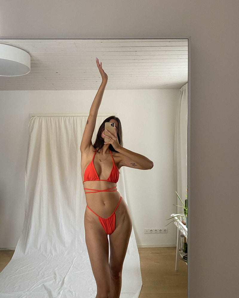 The Isola top in Clementine is a triangle shaped bikini top with a wrap around feature and adjustable neck tie that can be worn in various different ways.  The Isola bikini top has luxurious features which include movable ruched design and double lining for comfort and support. Mix and match the Isola Clementine bikini top with any Sundaze the Label bikini bottoms. 